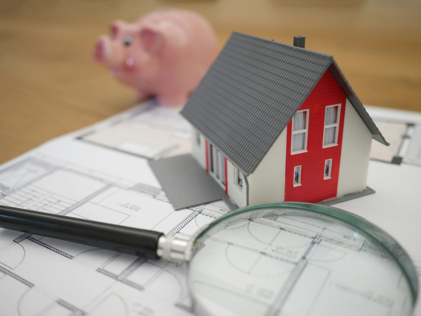Model house with a piggy bank and blueprints, representing mortgage savings